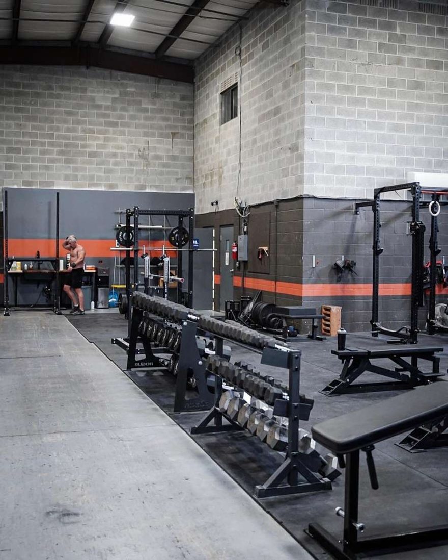 Dumbbell row, flat and incline benches, and power racks across the open training floor at The Forge Gym.